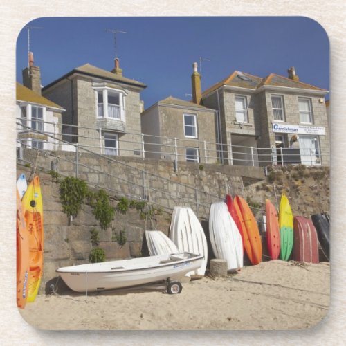 Kayaks and dinghies stacked against seawall at coaster