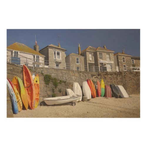 Kayaks and dinghies stacked against seawall at wood wall art