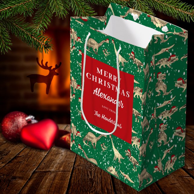 Kids Personalized Christmas Dinosaurs in the Snow Medium Gift Bag (Personalized boys name christmas dinosaurs in the snow red and green gift bag Dino wearing santa hat)