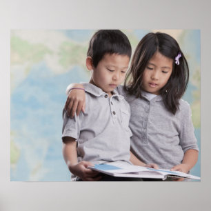 Korean children reading book near map poster
