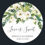 Love Is Sweet Greenery White Floral Wedding Classic Round Sticker<br><div class="desc">Floral wedding favor stickers with a top border featuring hand painted watercolor white roses and greenery with the message, "Love Is Sweet" in a lovely handwritten script and your names and date below. These elegant stickers are perfect for a garden wedding in the summer and are a great way to...</div>