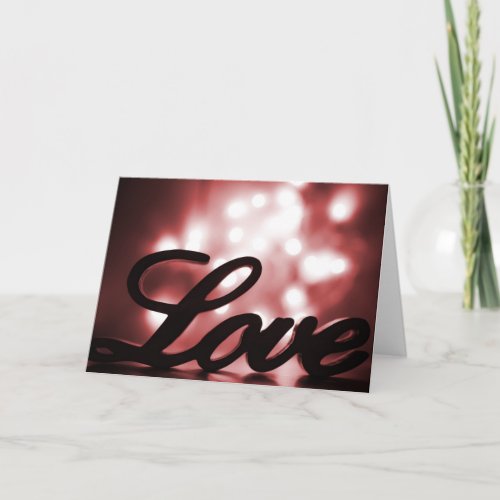 Love sign with red sparkle lights behind holiday card