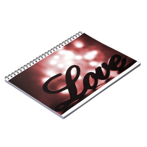 Love sign with red sparkle lights behind notebook