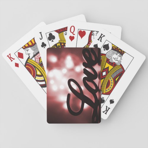 Love sign with red sparkle lights behind playing cards