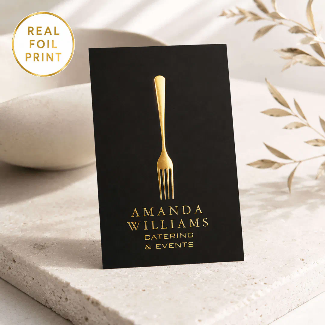 A black business card with a gold foil printed fork in gold text to match. The background includes different neutral tones.