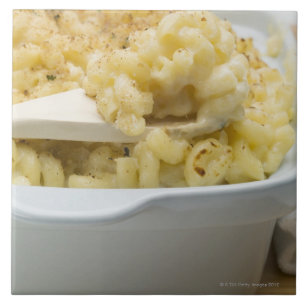 Macaroni cheese in baking dish with wooden tile