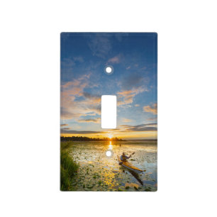 Male kayaker paddling sea kayak on still water light switch cover