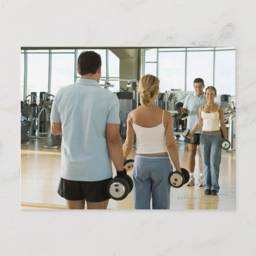 Man and woman lifting hand weights in front of a postcard