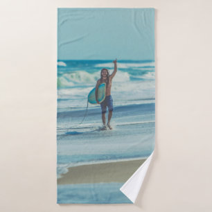 Man carrying surfboard at beach bath towel