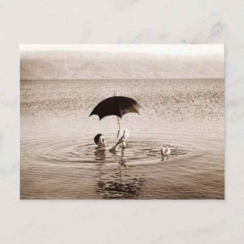 Man reading under umbrella in the Dead Sea Postcard