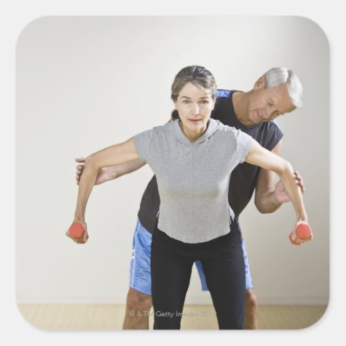 Mature man assisting woman exercising using square sticker