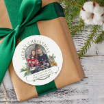 Merry Christmas Family Photo Holly and Pine Classic Round Sticker<br><div class="desc">Merry Christmas stickers with photo and traditional bouquets of holly, pine and pine cone. The colors of the text and background can be changed in the design tool. Your photo is displayed in 16:9 portrait format and the photo template will automatically display them in a pill-shaped, rounded lozenge shape. Please...</div>