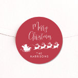 Merry Christmas Santa Reindeer Sleigh Red Classic Round Sticker<br><div class="desc">Fun seasonal red and white sticker for your Christmas holiday cards and gifts featuring a silhouette of reindeers flying Santa's sleigh through air,  "Merry Christmas" in a modern script and your name in simple typography.</div>