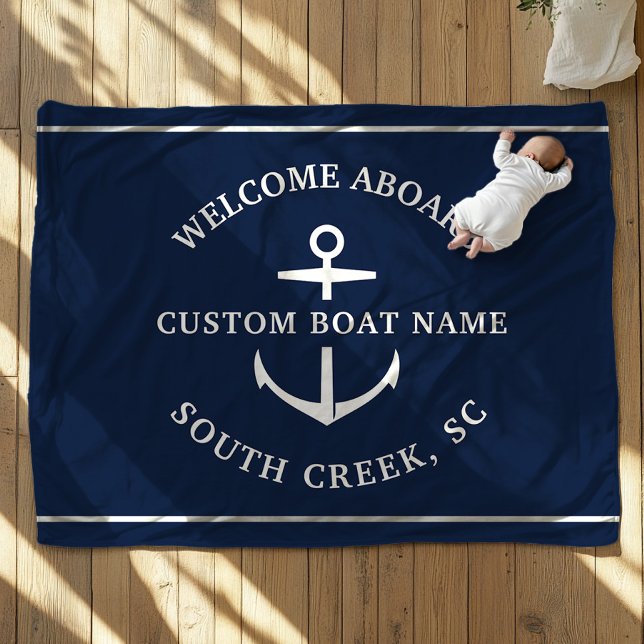 Modern Custom Boat Name Welcome Aboard Anchor Fleece Blanket (A baby, dressed in white, lies on a navy blue blanket with an anchor motif. Text is Welcome Aboard")