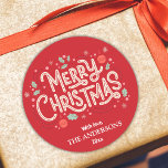 Modern festive cute red & white Merry Christmas  Classic Round Sticker<br><div class="desc">Celebrate the holidays in style with this modern sticker featuring a bright red background and cheerful white and red typography. The "Merry Christmas" message is adorned with holly, snowflakes, and baubles, creating a playful yet elegant design. Customizable with your family name and year, this sticker is perfect for adding a...</div>