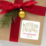Modern Gold Script Merry Christmas Custom Square Sticker<br><div class="desc">Stylish Merry Christmas holiday favor sticker features antique gold script writing and accents of green branches with holly leaves and red berries. Personalize with custom name / family and year text. The white background color can be modified.</div>