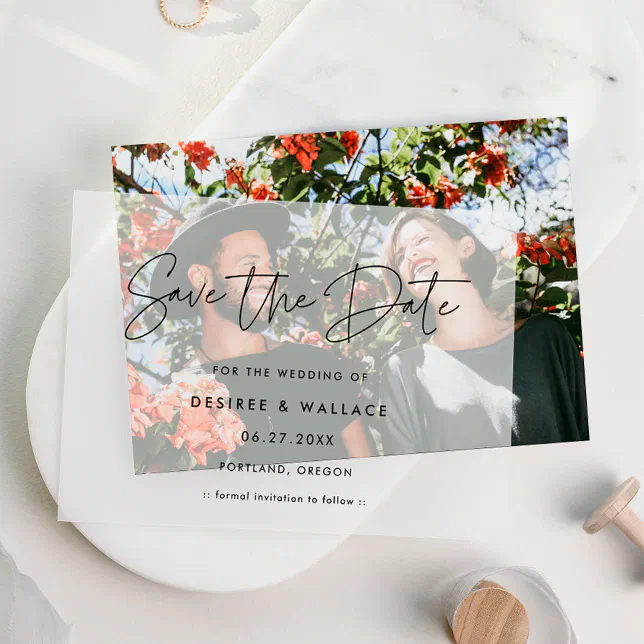 A Save the Date with a vellum overlay is lying on a plate. A couple is shown standing under a tree. 