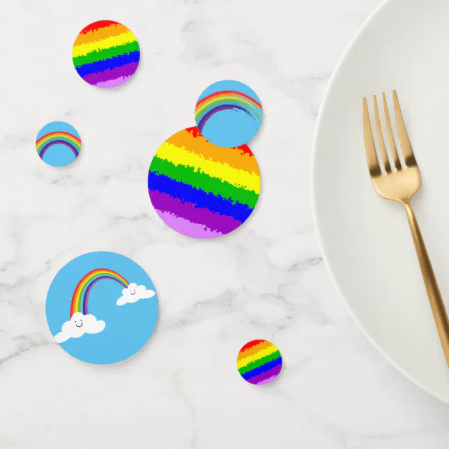 Table confetti with various rainbow motifs scattered by a white plate with a gold fork. 