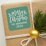 Modern Script Green Merry Christmas Custom Square Sticker<br><div class="desc">Stylish Merry Christmas holiday favor sticker features white script writing and accents of branches with holly leaves and berries. Personalize with custom name / family and year text. The green background color can be modified.</div>