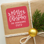 Modern Script Red Merry Christmas Custom Square Sticker<br><div class="desc">Stylish Merry Christmas holiday favor sticker features white script writing and accents of branches with holly leaves and berries. Personalize with custom name / family and year text. The crimson red background color can be modified.</div>