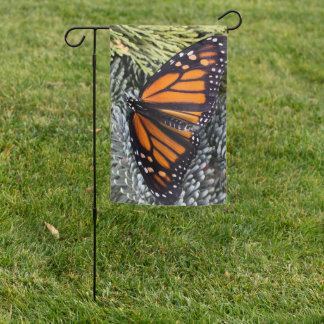 Monarch butterfly on evergreens garden flag
