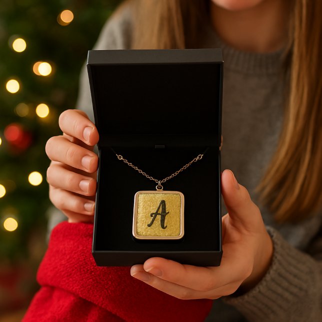 Monogram Gold  Sparkle  Plated Necklace (a girl gently holding the open gift box with the gold "A" necklace nestled inside, a plush red stock)