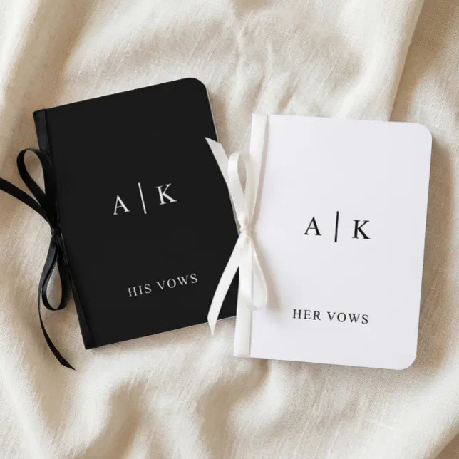 A pair of black and blue vow books rest atop a white sheet. 