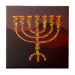 Moshe's Menorah Tile<br><div class="desc">A fiery seven-branched menorah superimposed on a dark mountainous background. In the Torah Moshe Rabbenu is told, "You shall make a Menorah of pure gold, beaten out, shall the Menorah be made, its base, its branch, its goblets, its knobs, and its flowers shall be hammered from it, " [Shmot 25:31]...</div>