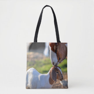 Mother goat kissing her baby on head. tote bag