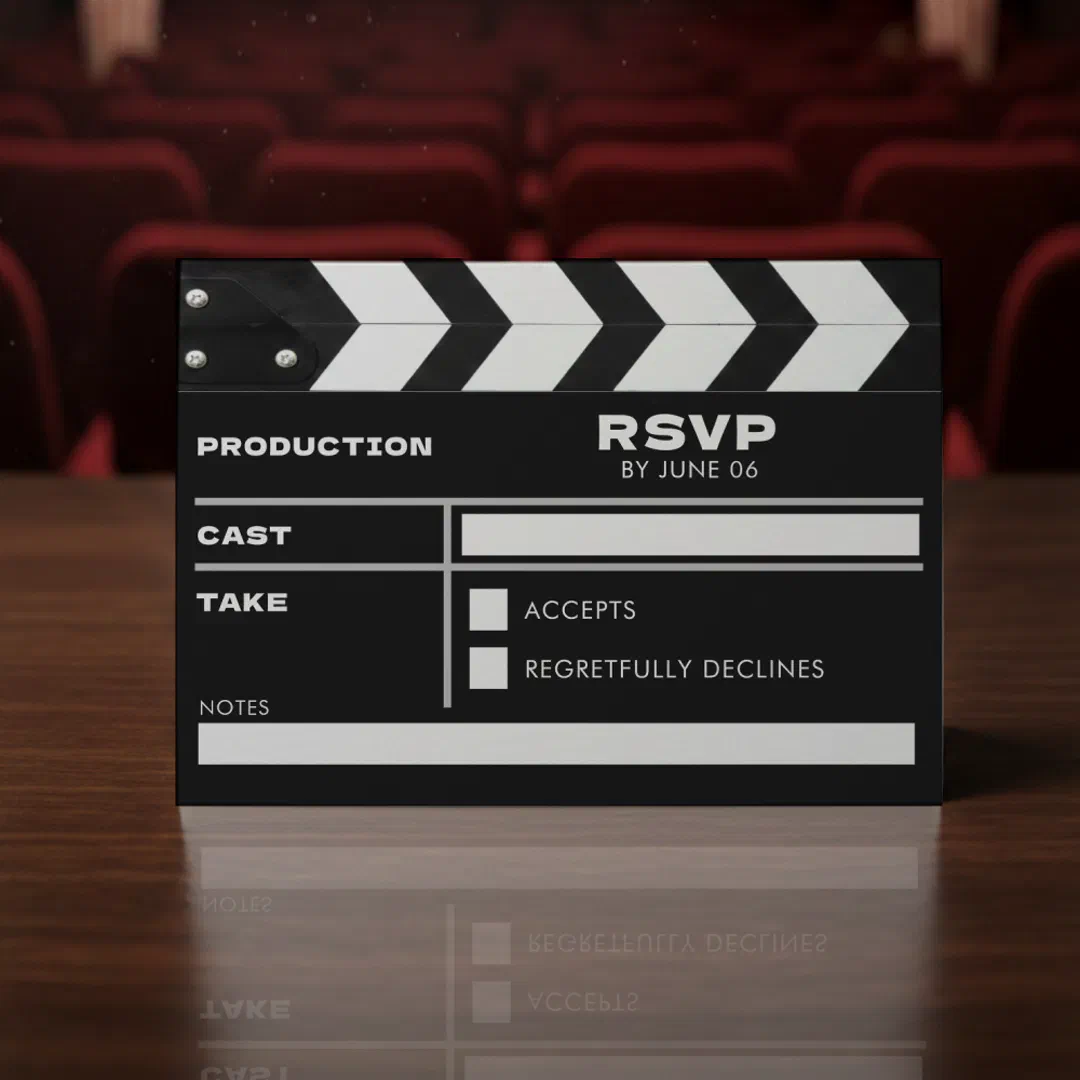 Black and white film clapboard RSVP card with checkboxes for accepts and regretfully declines, displayed against theater seats.
