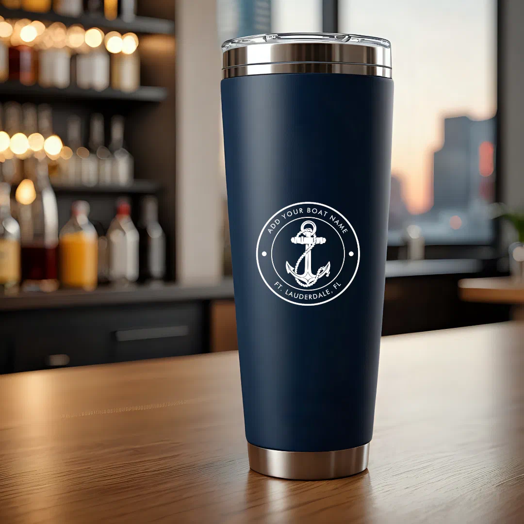 A navy stainless steel tumbler with white text placed in the middle of a dark brown counter with a bar area out of focus. 