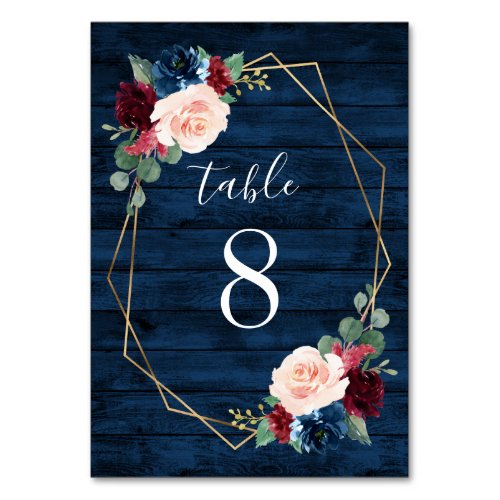 Navy and Burgundy Gold Blush Wedding Table Numbers - Navy Blue Burgundy Gold Blush Pink Country Wedding Table Number Cards - feature a dark navy blue barn or wood grain background decorated with a printed gold geometric frame that's trimmed with floral and greenery elements in shades of navy, pink, burgundy and more. View the matching collection on this page to find coordinating items.