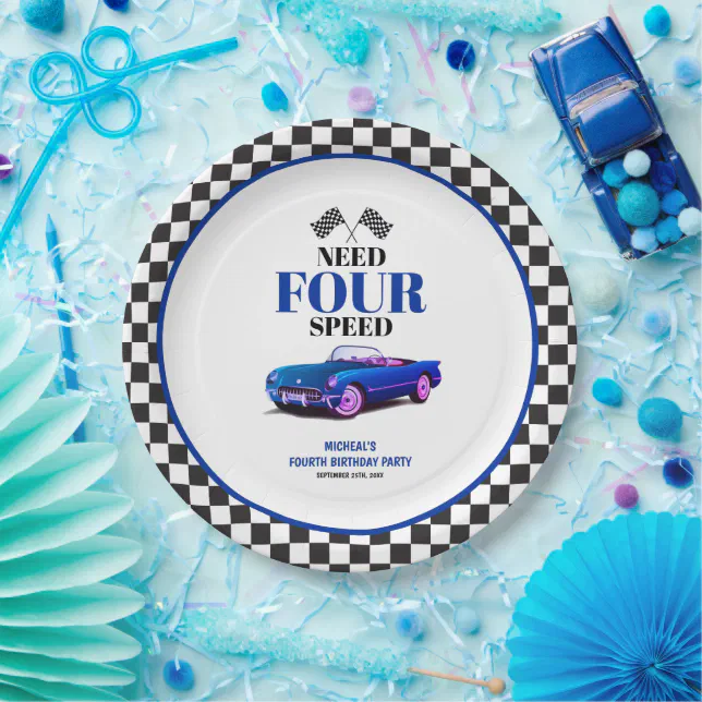 A messy blue background with various party supplies. The paper plate is the main focus with a black and white checkered border with a royal blue round circle. There's a blue car printed in the middle.