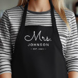 Newlywed Bride Personalized Black Mrs Apron<br><div class="desc">For the bride and groom, this black apron features "Mrs." in a modern script font along with a last name and established date. This is a perfect bridal shower or wedding gift. These Mrs. and Mr. aprons are available in a variety of colors and can be also customized to match...</div>