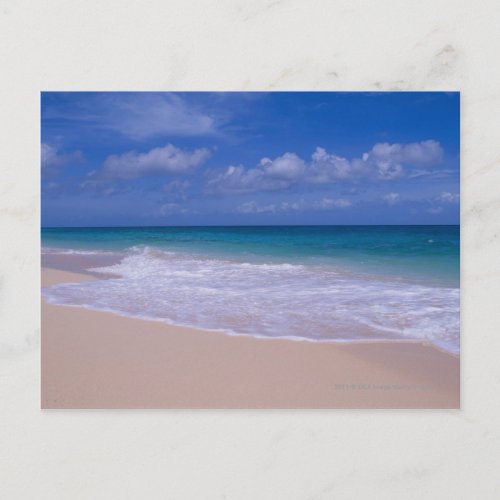 Ocean waves foaming onto sandy beach postcard