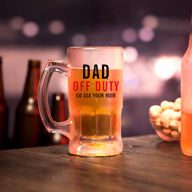 A Father's Day themed mug pictured on a bar countertop. Food and other drinks can be seen in the background, and hazy lights are flashing in the background as well.