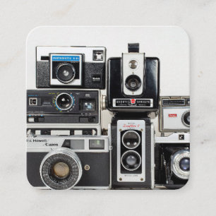 old camera collection stacked on white square business card