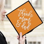 Orange | Thanks Mom and Dad Graduation Cap Topper<br><div class="desc">Thank your parents for their support by wearing a custom graduation cap topper in their honor. The stylish graduation cap topper features "Thanks Mom and Dad" in a trendy modern script font against an orange background.</div>