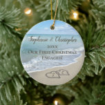 Our First Christmas Engaged Beach Hearts in Sand Ceramic Ornament<br><div class="desc">Celebrate your engagement while planning a beach wedding or honeymoon with this keepsake engagement ornament. Interlocking beach wedding hearts drawn in the sand makes an elegant tropical ocean coastal nautical theme wedding,  matching set of items. Pretty turquoise water waves crashing on the shore and pastel blue sky.</div>