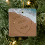 Our First Christmas With Names Beach Dated Ceramic Ornament<br><div class="desc">Nautical Boutique Co.'s "Our First Christmas" beach ornament features your names in sand writing (because that's tropical, right?!), the phrase "Our First Christmas" (of course!), and is dated on the reverse site. Two little watercolor seashells accent the design, and waves are gently rolling in over the heart drawn in the...</div>