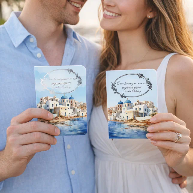 A couple pictured holding honeymoon-themed vow books. 