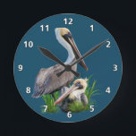 Pair of Brown Pelicans, Customizable Round Clock<br><div class="desc">A pair of Brown Pelicans, one standing and one sitting, relax by water’s edge. There's plenty of room on the image to customize with your own caption. If the background is a solid color, it is real easy to change it to any color you want. Just click on customize.Grass clumps...</div>