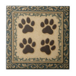 Paw Prints Ceramic Tile<br><div class="desc">Artwork of four cute paw prints. Celebrate your love for pets with this charming decorative tile featuring four adorable paw prints. Framed by an elegant, ornate border in a sophisticated deep teal and metallic gold, the central square boasts a warm, speckled cream background that beautifully highlights the dark brown paw...</div>