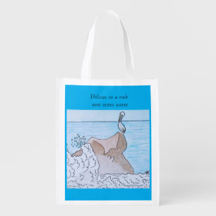 Pelican on a rock near ocean waves grocery bag