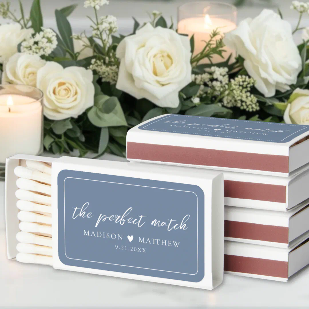 A personalized wedding matchbox with a soft periwinkle blue background, surrounded by delicate floral arrangements.