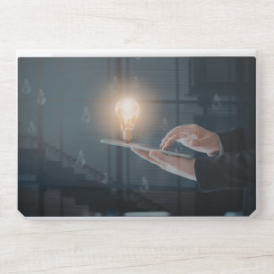 Person Holding Tablet with Glowing Lightbulb Symbo HP Laptop Skin