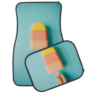 Person holding yellow and brown ice cream cone car floor mat