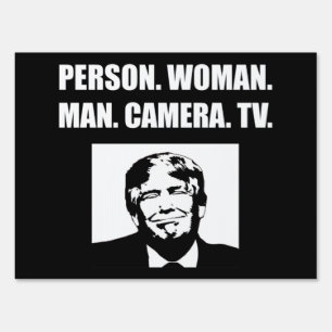 Person. Woman. Man. Camera. TV. Anti-Trump Sign