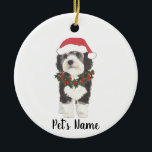 Personalized Bernedoodle Red and Green Christmas Ceramic Ornament<br><div class="desc">I am in love with this beautifully detailed watercolor illustration of a grey, black, and white bernedoodle or sheepadoodle on an ornament with a sweet santa hat and red and green holly wreath outfit! Personalize these pastel ornaments and make the nice list this year! For the perfect presents, pair it...</div>