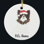 Personalized Black & White Papillon Christmas Ceramic Ornament<br><div class="desc">Make the nice list this year with a personalized Christmas ornament of your sweet black and white papillon in a santa hat and red and green holly wreath! For the sweetest gifts,  pair it with a matching art print or another item from my collection!</div>
